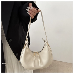Detail of creamy white crescent shoulder bag with dual zippers and gold hardware