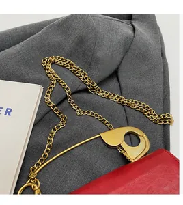 Detalle de bolso de cuero rojo con imperdible dorado y correa de cadena elegante