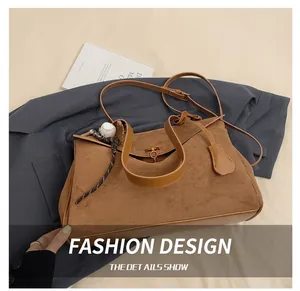 Detail of brown suede tote bag with metal twist lock and baseball charm decoration