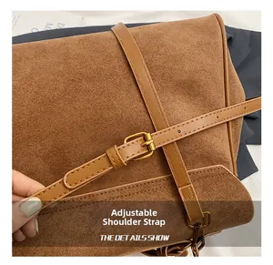 Detail of adjustable shoulder strap with golden metal buckle on brown suede tote bag