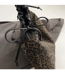 Detail of leopard print canvas bag with black faux leather drawstring and pleated texture