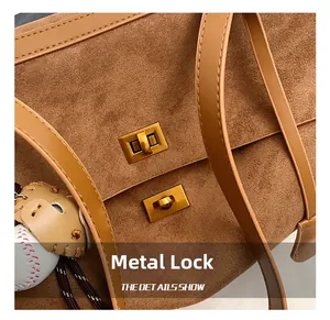 Close-up of brown suede tote bag featuring a golden hardware lock and baseball charm