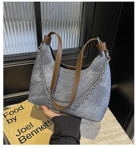 Nahaufnahme der hellblauen Denim-Hobo-Bag mit Vintage-Metallkette und braunem Lederriemen