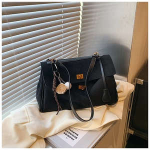 Close-up of black matte tote bag with dual gold metal locks and baseball charm detail