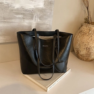 Black large capacity tote bag with textured crinkle leather and heart charm detail