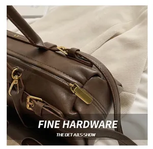 Detailed close-up of dark brown leather underarm bag with elegant gold-tone metal hardware