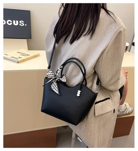 Sac seau noir en cuir grainé avec foulard en soie porté par un mannequin chic
