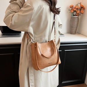 Chic brown bucket bag with metal handle and shoulder strap shown in a lifestyle setting