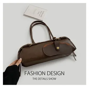 Detail showing the dark brown leather texture and unique flap design of the shoulder bag
