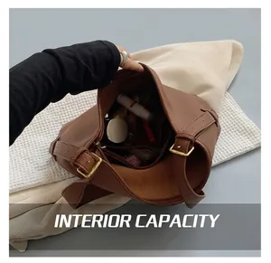 Detail view of the spacious inner compartment and golden hardware buckle on the brown bag