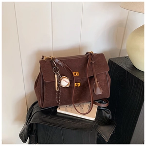 Macro detail of dark brown suede tote bag with golden twist lock and baseball charm detail
