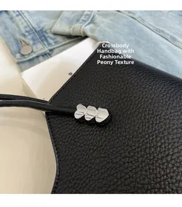 Détail du sac en cuir noir grainé avec boucles de cœur argentées et bandoulière fine