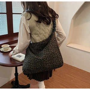 Detailed view of large leopard print hobo bag with black pleated strap on a model