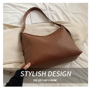 Close-up of brown litchi pattern leather hobo bag on soft white bedding texture