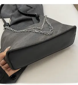 Detail der Schultertasche aus grauem Canvas und schwarzem Leder mit silbernen Ketten