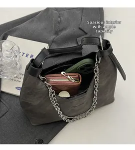 Detailansicht der grauen Wildleder-Beuteltasche mit Alltagsgegenständen und Silberkette