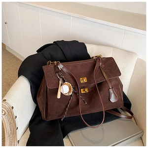 Detail of dark brown suede tote bag with golden twist lock and baseball charm detail