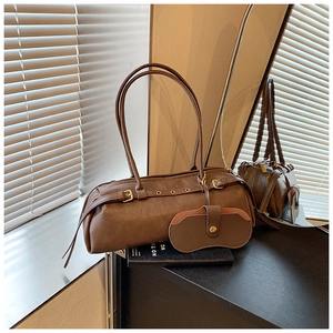 Detail of dark brown leather Boston bag with decorative buckle and matching mini pouch accessory