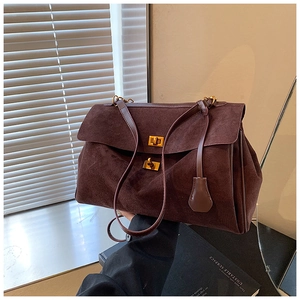 Close-up of deep brown suede tote bag featuring premium golden metal twist-lock hardware