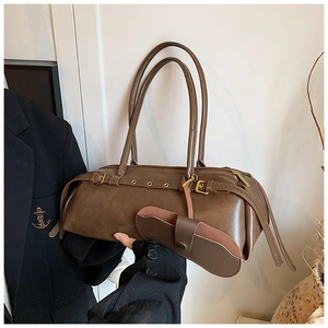 Macro detail of brown leather cylinder bag with vintage metallic eyelets and small pouch