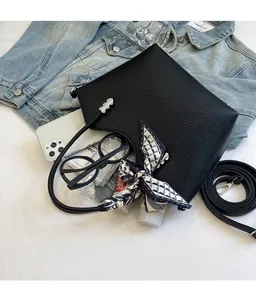 Détail du sac seau en cuir noir avec foulard en soie et boucle en métal en cœur