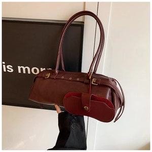 Detail view of burgundy leather baguette bag featuring golden buckles and mini pouch accessory