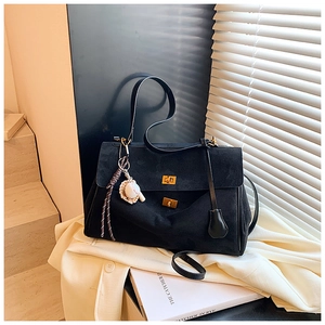 Detail of black suede tote with gold twist locks and unique baseball glove charm