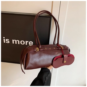Detail of burgundy leather bowling bag with adjustable buckle straps and mini pendant charm
