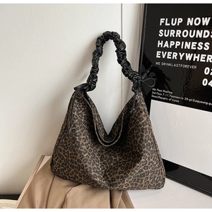 Detail of leopard print tote bag featuring black gathered leather shoulder strap and canvas texture