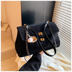 Detail of black suede tote with golden twist locks and a baseball charm accessory