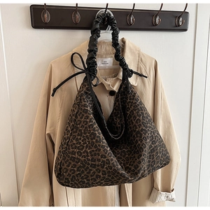Detail of leopard print tote bag featuring black scrunchie handle and drawstring accent