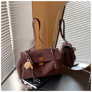 Detail of a brown suede tote bag with dual gold locks and creative sports charm