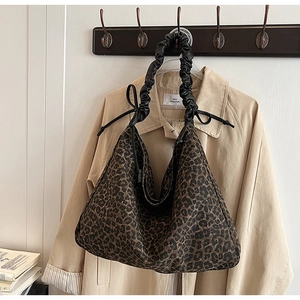 Detail of leopard print tote bag featuring black ruched handle and bow decoration