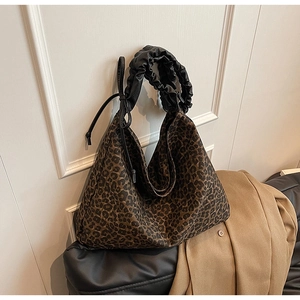 Detail of leopard print tote bag with black pleated strap and side drawstring accents