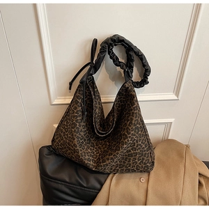 Detail of leopard print hobo bag featuring a stylish black ruched shoulder strap