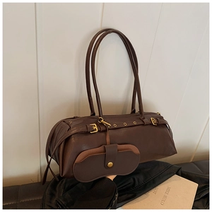 Detail of dark brown matte leather baguette bag with gold buckles and retro pillow shape