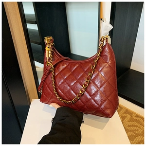 Detail of dark red quilted leather bag with gold chain and key-shaped charm