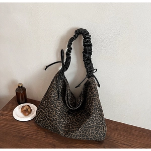 Detail of leopard print hobo bag featuring black gathered handle and drawstring accents