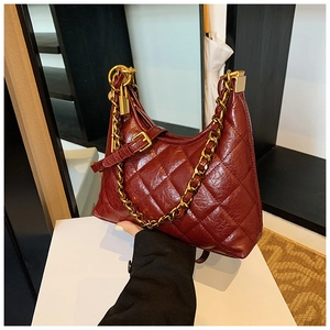 Detail view of burgundy quilted leather handbag with gold chain and polished finish
