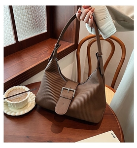 Detail of a brown pleated crescent bag featuring vertical texture and metal zipper closure