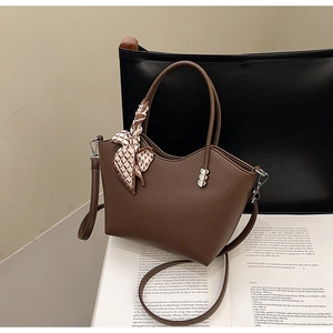 Détail du sac en cuir marron avec foulard en soie et boucles métalliques en forme de cœur