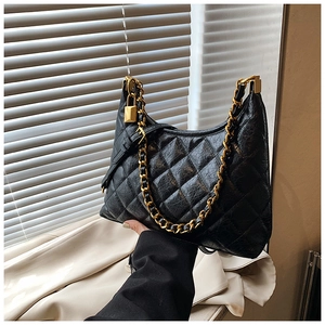 Detail of a black quilted hobo bag with vintage leather texture and gold chain strap