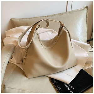 Close-up of beige lychee grain leather shoulder bag with gold zipper detail