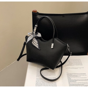 Détail du sac en cuir noir grainé avec quincaillerie en forme de cœur et foulard en soie