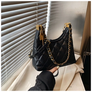 Close-up of black quilted hobo bag featuring gold chain and luxury metal hardware