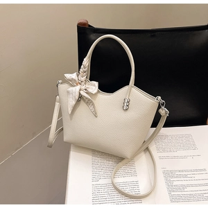 Détail du sac cabas en cuir grainé blanc crème avec foulard en soie et bijou cœur