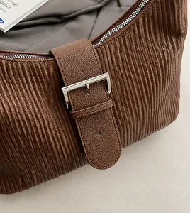 Detail of brown hobo bag showing vertical pleated texture and silver buckle hardware