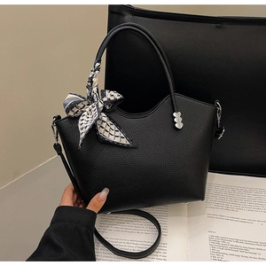 Détail d'un sac seau en cuir noir avec boucle cœur argentée et ruban de soie décoratif