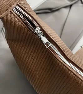 Close-up of smooth silver metal zipper on premium brown lychee texture leather bag