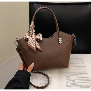 Gros plan sur sac seau en cuir grainé marron avec poignée en soie et breloques cœur